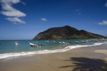 VENEZUELA, Margarita Island, Playa la Galera, View of exotic beach with palm trees and their shades on the sand, just in front of fishing boats floating at the tropical crystal clear seawaters, shot o...