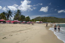 VENEZUELA, Margarita Island, Playa Caribe, View of exotic beach with people walking on the sand while colorful tents, deck chairs, bars, restaurants and palm trees are noticeable, on a bright day with...