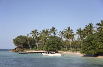 Domincan Republic, Samana Peninsula, Cayo Levantado, Bacardi island, Palm tree lined shore, wooden jetty and moored boat.