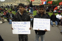 France, Paris, Esplanade des Invalides,Two boys stand in front of a protest of Tamil Tiger supporters, holding signs reading, Yesterday, more than 35000 civilians were killed by the Sri Lankan army, i...