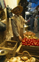 MOROCCO, Fez, Male stallholder behind crates of produce at the fruit market in the souk, pair of scales in the foreground.   