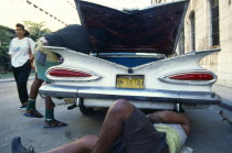 CUBA, Havana, Old Havana, Old American car being repaired in street.