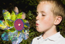 Children, Toys, Outdoors, Young boy blowing toy windmill gently.