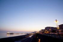 England, East Sussex, Brighton, Kemptown, view over Madeira Drive from Marine Parade with the pier illuminated at sunset. Skies clear due to no fly zone over uk because of Icelandic volcanic dust fear...