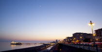 England, East Sussex, Brighton, Kemptown, view over Madeira Drive from Marine Parade with the pier illuminated at sunset. Skies clear due to no fly zone over uk because of Icelandic volcanic dust fear...