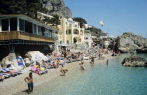 Italy, Campania, Capri, Tourists sunbathing on beach at Marina Piccola.