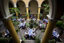 Cuba, Havana, Habana Vieja, San Ignacio 54, Plaza de la Catedral, interior of the open air restaurant El Patio with people eating and drinking.