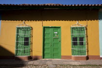 Cuba, Sancti Spiritus, Trinidad, Traditional colourfully house with orange painted walls and green door and iron protected windows.