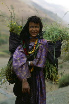 Morocco, Atlas Mountains, Berber girl with backpack carrying harvested crops.
