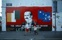 Ireland, North, Belfast, Irish Republican mural with an image of James Connelly on the side of a terrace house on the corner of Beechmount Road with children playing on the pavement sidewalk.