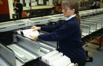 England, East Sussex, Brighton, Female Postal worker collecting sorted mail at the end of the OCR conveyor belt in the Post Office sorting depot.