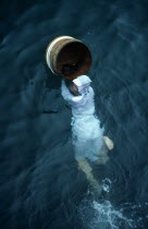 Japan, Honshu, Toba, Traditional female pearl diver swimming in the water with wooden barrel for collecting oysters at the Mikimoto Pearl Farm in Mie Prefecture in Kansai Region.