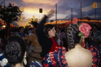 Spain, Andalucia, Seville, Female flamenco dancers dancing at sunset in traditional costume during the April Fair or Feria de Abril in the streets of the fairground in the Los Romedios District.