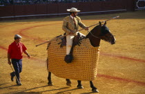 Spain, Andalucia, Seville, Picador with lance riding a padded and blindfolded horse in the bullring at a bullfight in Arenal District.