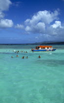West Indies, Caribbean, Tobago, Tourists swimming in the shallow water beside a glass bottomed boat in the Nylon Pool in Buccoo Reef a coral reef in the marine park.