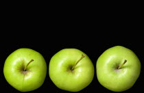 Food, Fruit, Apples, Three ripe green apples in a line seein from above showing the storks or stems against a black background.