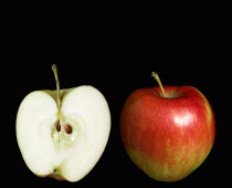 Food, Fruit, Apples, Two ripe red apples with one whole and one cut in half to show the core seeds and white flesh against a black background.