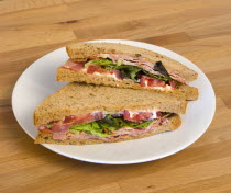 Food, Meal, Snack, Bacon lettuce and tomato BLT sandwich on a white plate on a wooden table top.