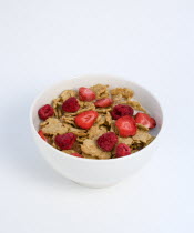 Food, Meals, Cereals, White breakfast bowl of bran flake cereal with freeze dried fruits of strawberries and raspberries in milk on a white background.