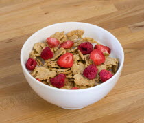 Food, Meals, Cereals, White breakfast bowl of bran flake cereal with freeze dried fruits of strawberries and raspberries in milk on a wooden table.