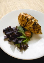 Food, Cooked, Chicken, Roasted chicken breast portion on a white plate with a leaf salad garnish.