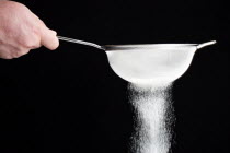 Food, Baking, Flour, White plain flour being siifted through a sieve against a black background.