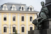 Poland, Krakow, Detail of male figure on monument to the polish romantic poet Adam Mickiewicz by Teodor Rygier in 1898 in the Rynek Glowny market square with pastel coloured building in the background...