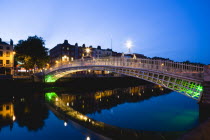 Ireland, County Dublin, Dublin City, The 1816 cast iron Ha Penny or Half Penny Bridge across the River Liffey illuminated at sunset.