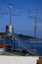 Environment, Energy, Solar Power, Solar power panel amongst aerials on the roof of a house in Greece.