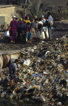 Egypt, Cairo, People standing beside rubbish tip in the Imbaba area of the city.
