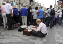 Scotland, Lothian, Edinburgh Fringe Festival of the Arts 2010, Street performers and crowds on the Royal Mile, performer using typewriter as part of his act.