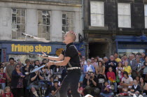 Scotland, Lothian, Edinburgh Fringe Festival of the Arts 2010, Street performers and crowds on the Royal Mile, man juggling knives.