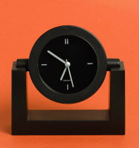 Time, Clocks, Analogue, Battery powered black analogue quartz table or desk clock against a red background.
