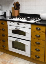 Architecture, Interiors, Kitchen, White domestic gas hob and electric oven household appliance set under worktop in fitted integrated kitchen.