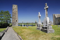 Ireland, County Offaly, Clonmacnoise, Monastery Round tower with row of crosses and River Shannon in the background.