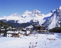 Switzerland, Arosa, Ski resort with people skiing in the foreground and the Alps behind.