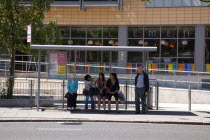 Ireland, North, Belfast, University Road, People sat at busstop waiting for bus.