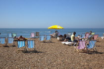 England, East Sussex, Brighton, Deck chairs and sunbathers on the pebble beach.