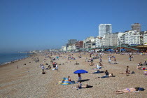 England, East Sussex, Brighton, people sunbathing on the pebble beach.