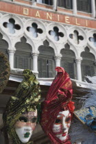 Italy, Veneto, Venice, Red, green, blue and gold carnival masks in front of partly seen facade of the Hotel Danieli.