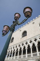 Italy, Veneto, Venice, Decorative street lamp in front of partly seen facade of the Palazzo Ducale against cloudless blue sky.