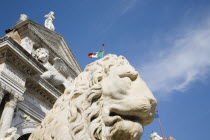 Italy, Veneto, Venice, Centro Storico, Arsenale, Castello with guardian lion statue in foreground and Italian tricolour flag against blue sky of late summer.