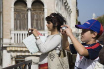 Italy, Veneto, Venice, Mother and son take photographs of canal view opposite St. Mark's