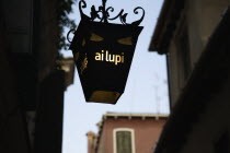 Italy, Veneto, Venice, Centro Storico, Lantern outside restaurant inscribed with ai lupi which translates as to the wolves with reference to Dantes use of wolves as metaphor in the Inferno.