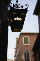 Italy, Veneto, Venice, Centro Storico, Lantern outside restaurant inscribed with ai lupi which translates as to the wolves with reference to Dantes use of wolves as metaphor in the Inferno.