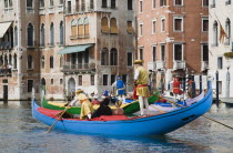 Italy, Veneto, Venice, Grand Canal, Participants in the Regata Storico annual historical regatta in brightly painted gondolas and wearing traditional costume approaching the Rialto bridge with onlooke...