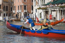 Italy, Veneto, Venice, Grand Canal, Participants in the Regata Storico historical Regatta in brightly painted gondolas and wearing traditional costume approaching the Rialto bridge with onlookers on b...