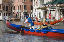 Italy, Veneto, Venice, Grand Canal, Participants in the Regata Storico historical Regatta in brightly painted gondolas and wearing traditional costume approaching the Rialto bridge with onlookers on b...
