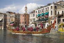 Italy, Veneto, Venice, Grand Canal, Participants in the Regata Storico historical Regatta held each September, in red and gold decorated gondola, wearing traditional costume approaching the Rialto bri...