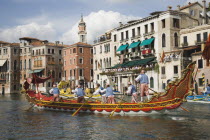 Italy, Veneto, Venice, Grand Canal, Participants in the Regata Storico historical Regatta held each September rowing red and gold decorated gondola and wearing traditional costume, approaching the Ria...